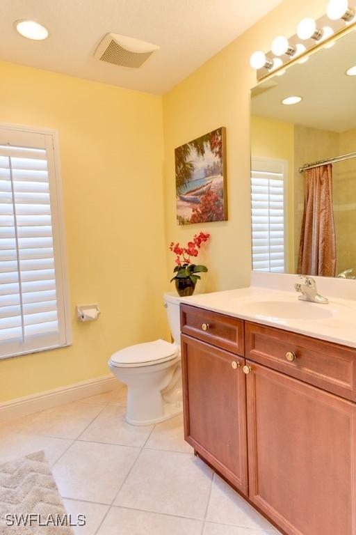 full bathroom featuring curtained shower, tile patterned flooring, toilet, vanity, and baseboards