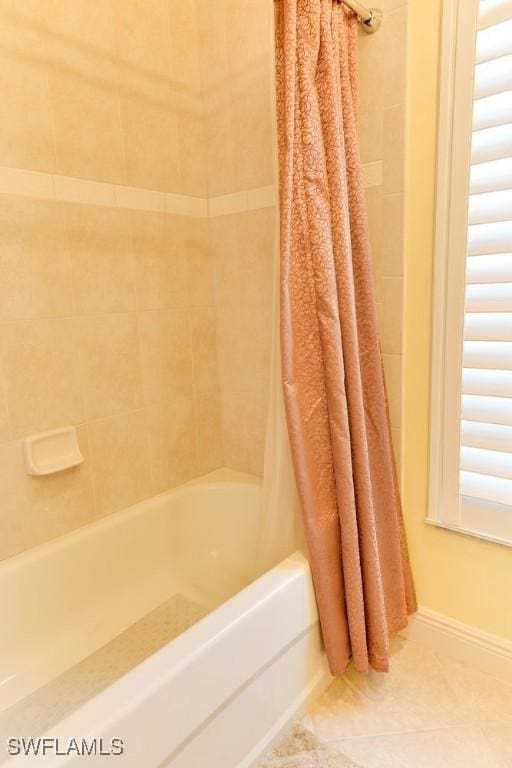 bathroom featuring baseboards, shower / bath combo with shower curtain, and tile patterned floors