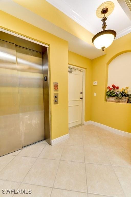 hallway with light tile patterned floors, crown molding, baseboards, and elevator