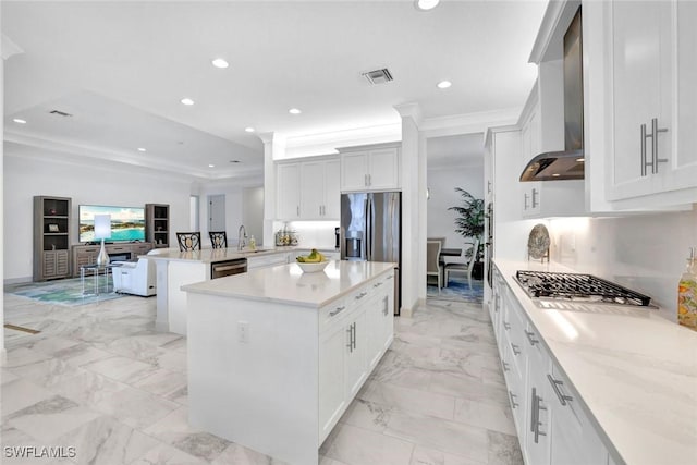 kitchen with recessed lighting, visible vents, appliances with stainless steel finishes, a sink, and wall chimney range hood