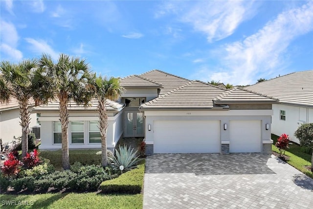 view of front of home with decorative driveway, an attached garage, and stucco siding