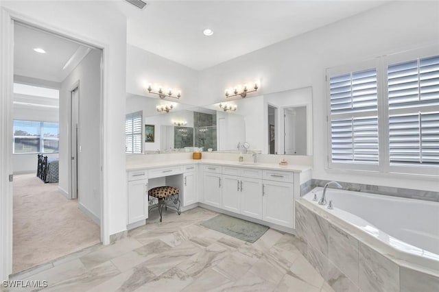 bathroom with a garden tub, vanity, and baseboards