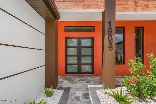 view of exterior entry featuring stucco siding and french doors