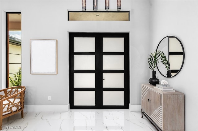 foyer entrance featuring marble finish floor and baseboards