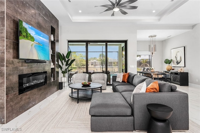 living area with recessed lighting, a raised ceiling, a fireplace, and ceiling fan