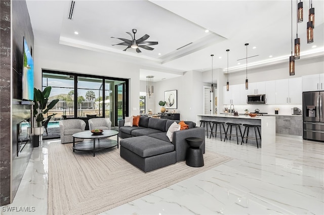 living room with recessed lighting, a towering ceiling, a ceiling fan, marble finish floor, and a raised ceiling