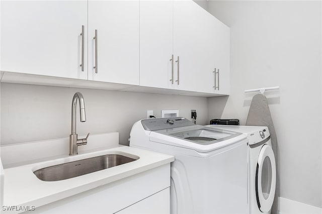 washroom with cabinet space, independent washer and dryer, and a sink