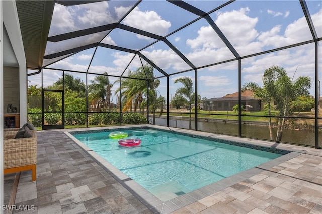 outdoor pool with a water view, glass enclosure, and a patio