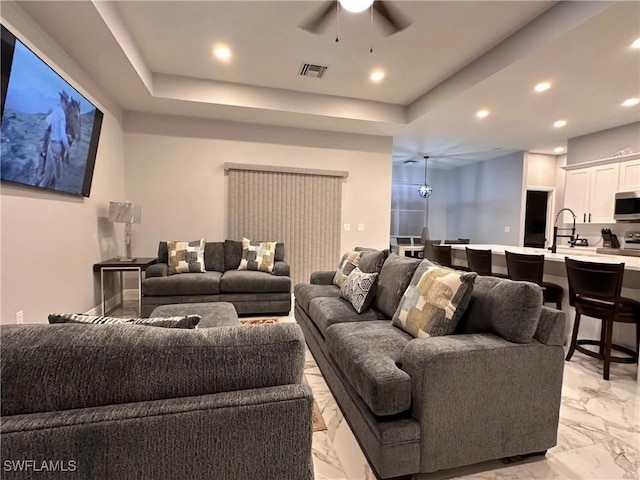 living room with recessed lighting, a raised ceiling, visible vents, and marble finish floor