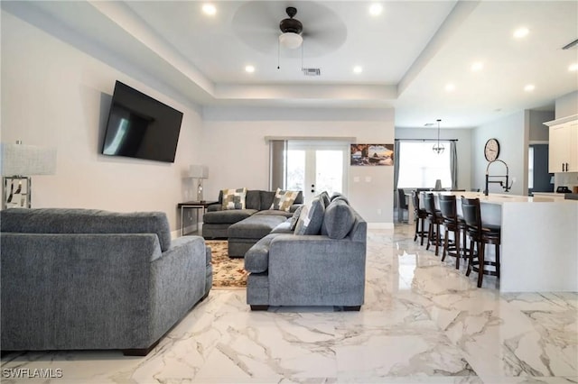 living area featuring visible vents, a ceiling fan, marble finish floor, a tray ceiling, and recessed lighting