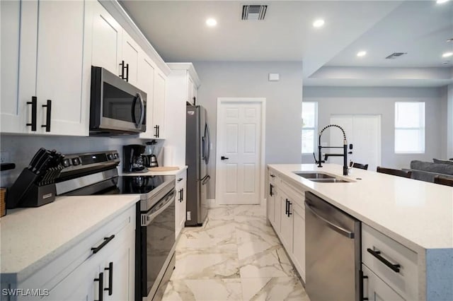 kitchen with appliances with stainless steel finishes, a sink, visible vents, and white cabinetry