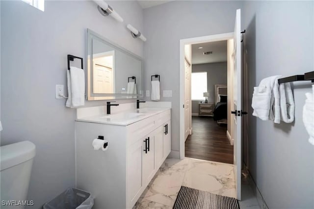 bathroom featuring toilet, visible vents, vanity, marble finish floor, and ensuite bath