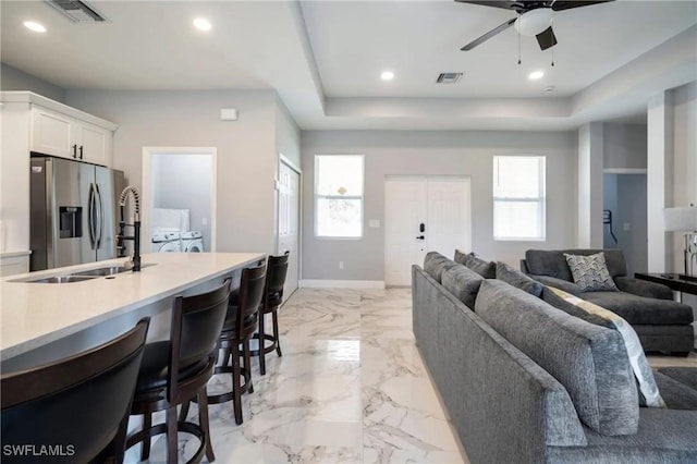 living area with a tray ceiling, a healthy amount of sunlight, and visible vents