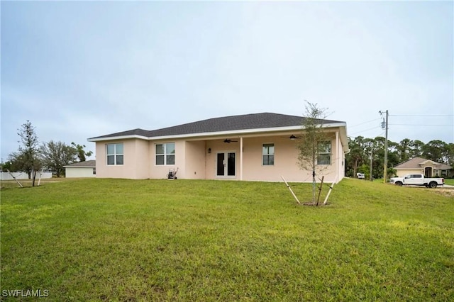 rear view of house with a lawn and stucco siding