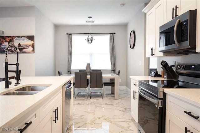 kitchen featuring white cabinets, stainless steel appliances, light countertops, and hanging light fixtures