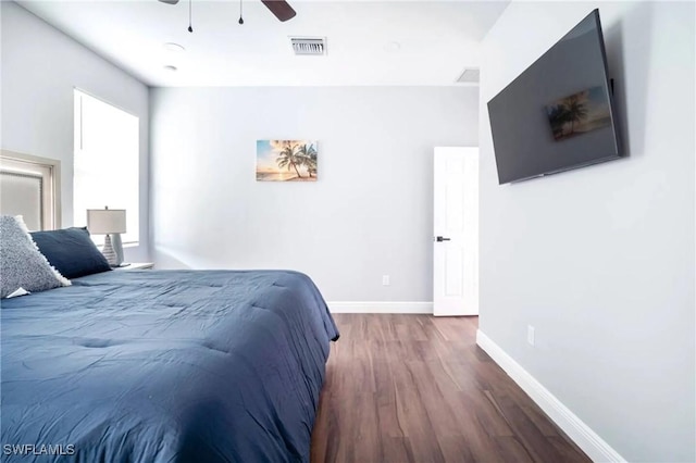 bedroom featuring a ceiling fan, visible vents, baseboards, and wood finished floors