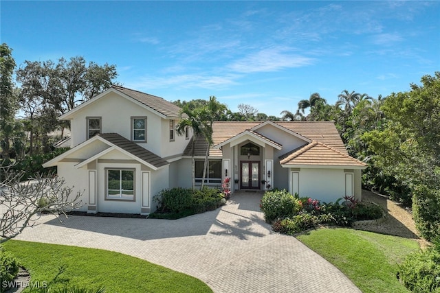 view of front of house featuring french doors, a tiled roof, a front lawn, and stucco siding