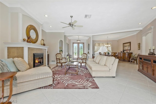 living area featuring light tile patterned floors, visible vents, a glass covered fireplace, crown molding, and recessed lighting