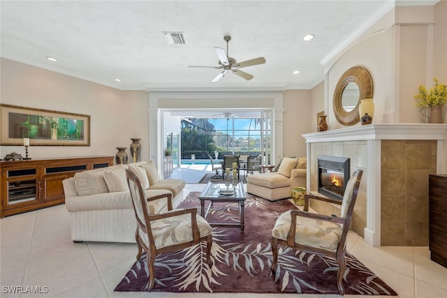 living area with light tile patterned floors, visible vents, a tiled fireplace, crown molding, and recessed lighting