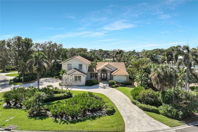 view of front of property featuring a tile roof, a front lawn, decorative driveway, and stucco siding