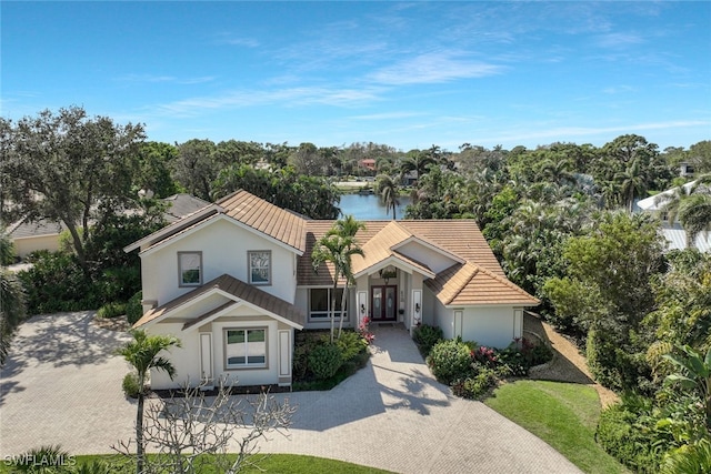 view of front of property featuring a water view, a tile roof, and stucco siding