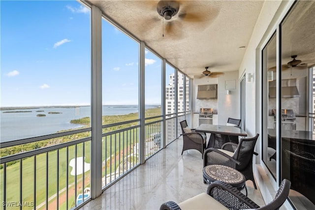 sunroom / solarium featuring a water view and ceiling fan