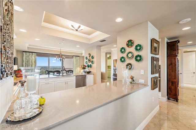 kitchen with a sink, white cabinets, ornamental molding, stainless steel dishwasher, and a raised ceiling