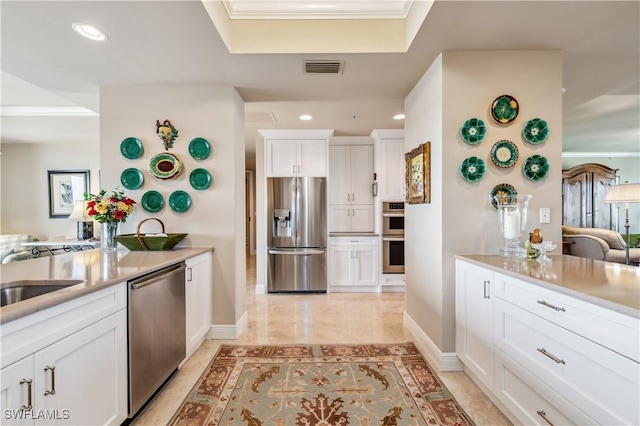 kitchen with appliances with stainless steel finishes, white cabinets, light countertops, and visible vents