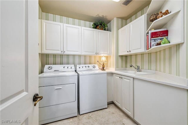 laundry room with cabinet space, wallpapered walls, visible vents, washer and clothes dryer, and a sink