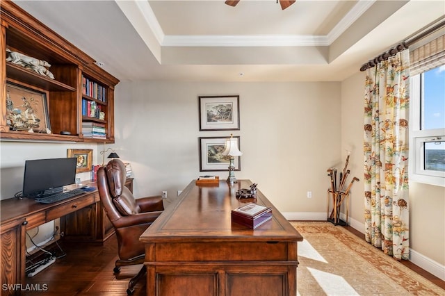 home office with wood finished floors, a ceiling fan, baseboards, ornamental molding, and a raised ceiling