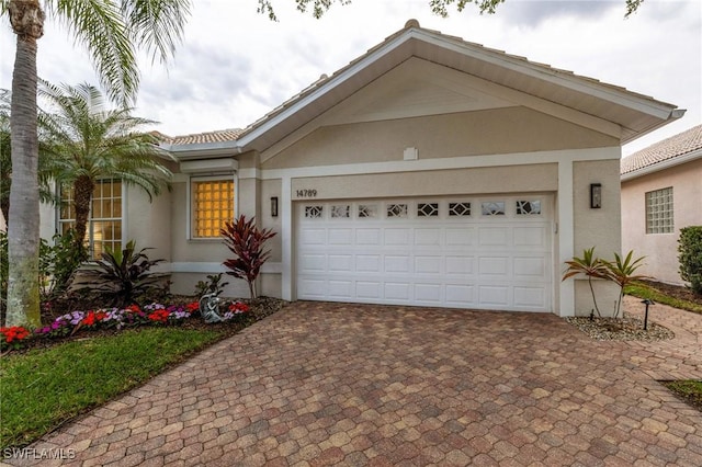 ranch-style house featuring a garage, decorative driveway, and stucco siding