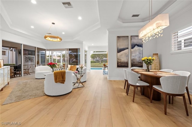 living area with a raised ceiling, visible vents, and light wood-style floors