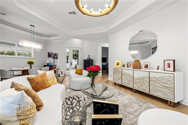 living area with visible vents, french doors, a tray ceiling, and ornamental molding