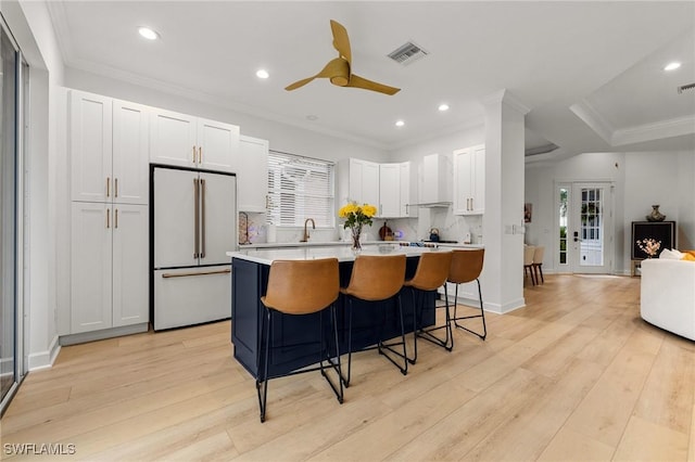 kitchen featuring high end white refrigerator, a center island, light countertops, visible vents, and white cabinetry