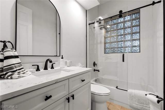 bathroom with enclosed tub / shower combo, vanity, and toilet