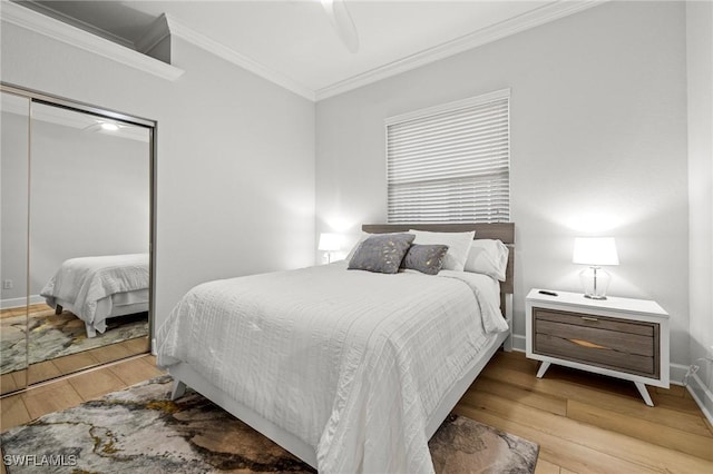 bedroom with baseboards, ceiling fan, ornamental molding, wood finished floors, and a closet