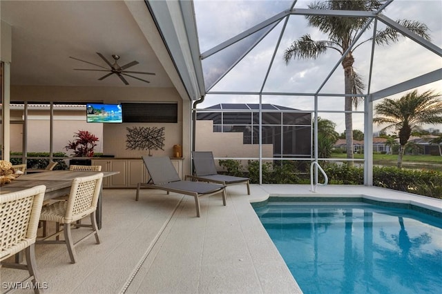 outdoor pool with glass enclosure, ceiling fan, a patio area, and an outdoor bar