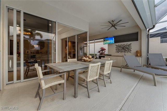 view of patio with glass enclosure, a ceiling fan, and outdoor dining space