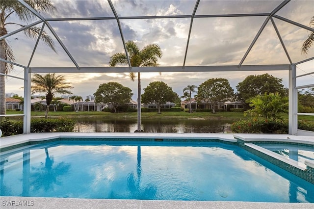 view of swimming pool featuring a lanai, a water view, and a pool with connected hot tub