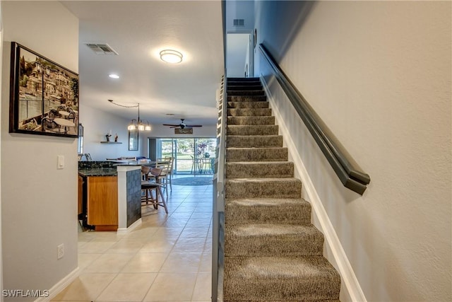 stairs featuring ceiling fan, baseboards, visible vents, and tile patterned floors