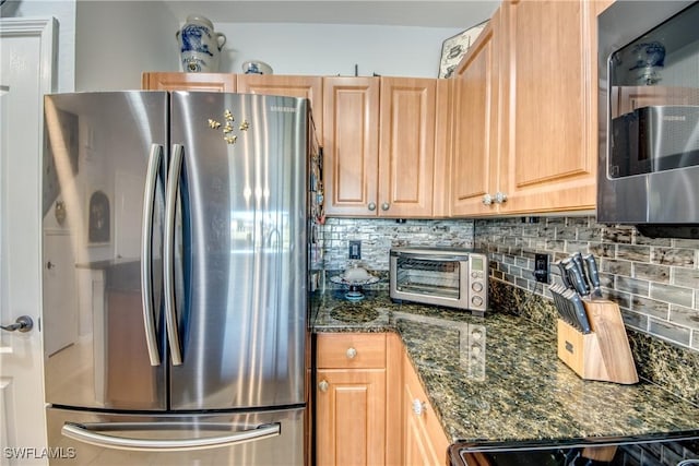 kitchen featuring dark stone counters, stainless steel appliances, a toaster, and decorative backsplash