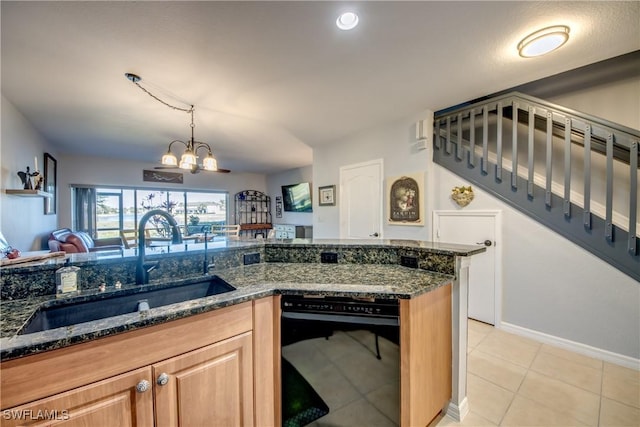 kitchen featuring light tile patterned floors, a notable chandelier, a sink, open floor plan, and dark stone countertops