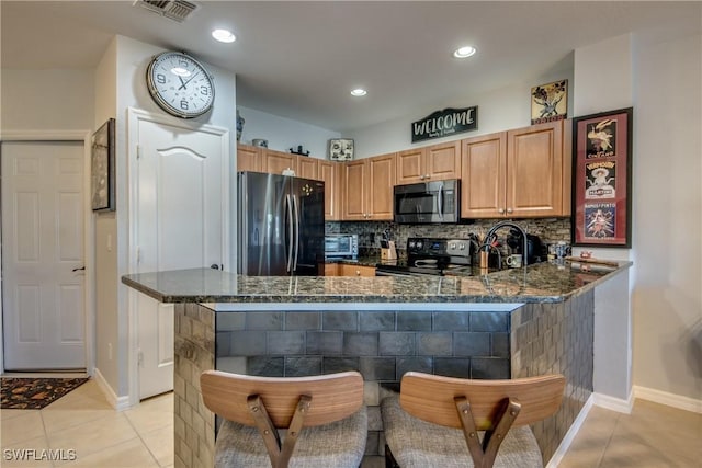 kitchen featuring tasteful backsplash, light tile patterned flooring, dark stone counters, a peninsula, and black appliances