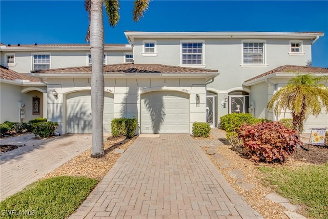 view of property featuring a garage, decorative driveway, and stucco siding