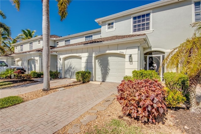 townhome / multi-family property featuring a garage, decorative driveway, and stucco siding