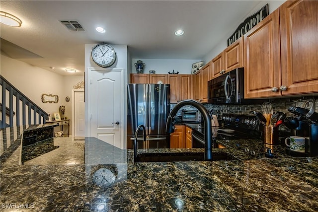 kitchen featuring black appliances, visible vents, backsplash, and dark stone countertops