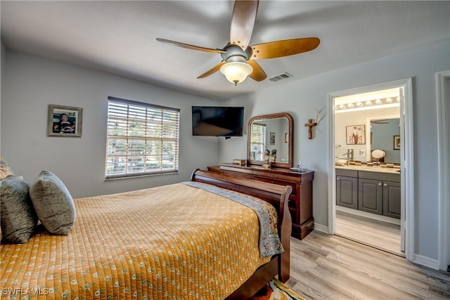 bedroom featuring light wood finished floors, visible vents, ensuite bathroom, a ceiling fan, and baseboards