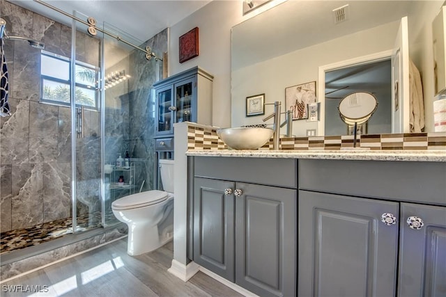 bathroom featuring toilet, a stall shower, wood finished floors, and vanity