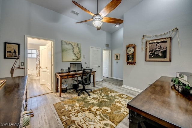 office with light wood-type flooring, high vaulted ceiling, ceiling fan, and visible vents