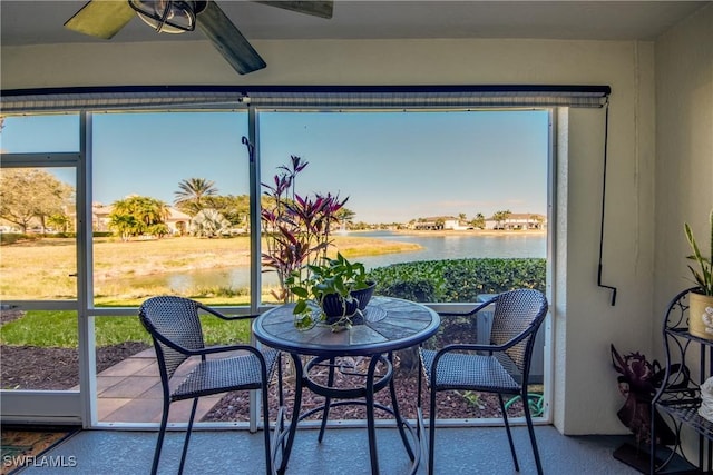 sunroom / solarium featuring ceiling fan and a water view